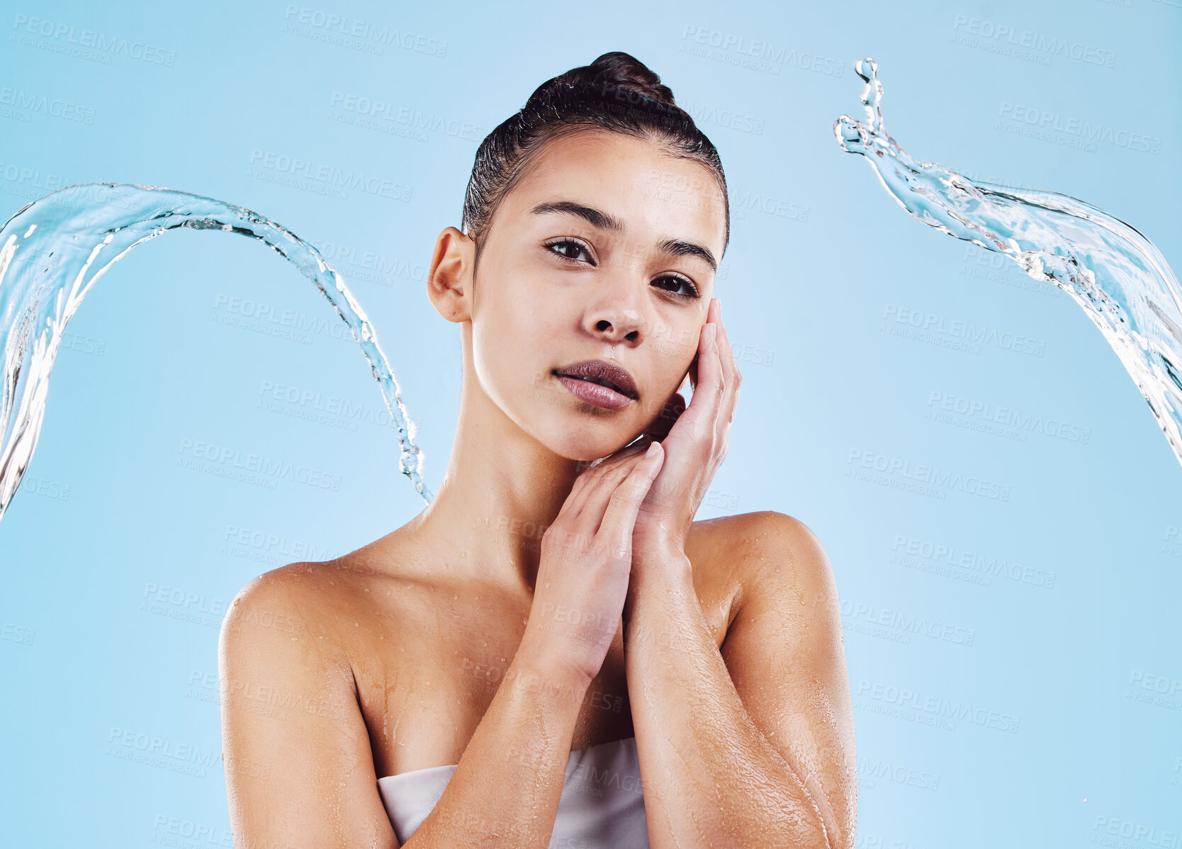 Buy stock photo Water splash, portrait and woman shower in studio, blue background and healthy beauty of natural skincare. Serious female model, wet and cleaning for hygiene, hydration and wellness on color backdrop