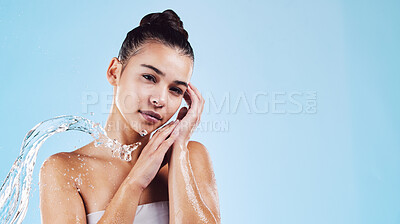 Buy stock photo Portrait, dermatology and woman with water splash, cleaning and beauty on a blue studio background. Face, female and person with clear liquid, morning routine and cosmetics for wellness and self care