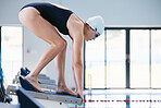Sports, swimming pool and woman on starting block ready for jump, exercise and training. Swimmer, athlete and person on diving board to dive, workout and swim in water for aquatic sport and fitness.