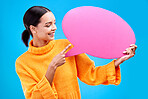 Speech bubble, smile and woman pointing to banner in studio for advertising on blue background. Happy, finger and female with poster, mockup and space for social media, announcement or billboard news