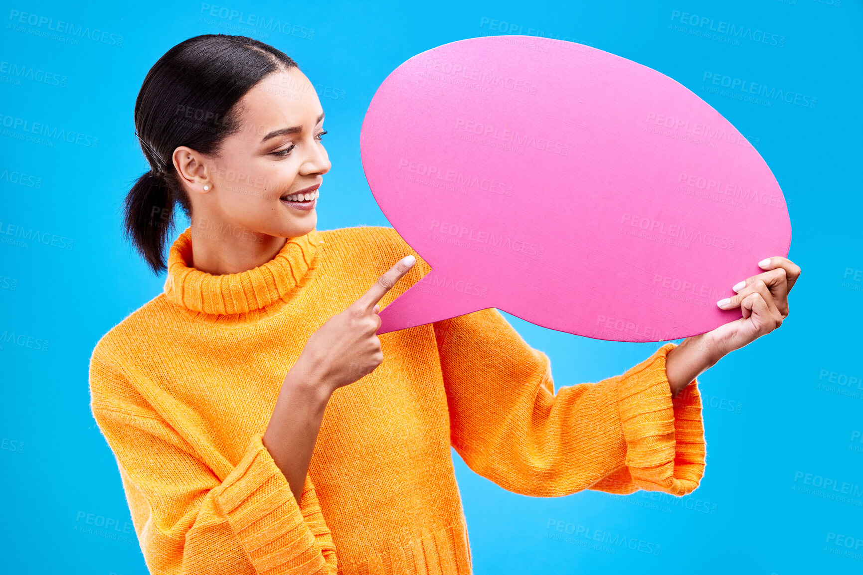 Buy stock photo Speech bubble, smile and woman pointing to banner in studio for advertising on blue background. Happy, finger and female with poster, mockup and space for social media, announcement or billboard news