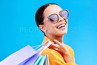 Buy stock photo Shopping bags, retail and woman portrait with a smile and sunglasses from boutique sale. Happy, customer and female model with store bag and sales choice in isolated blue background in studio