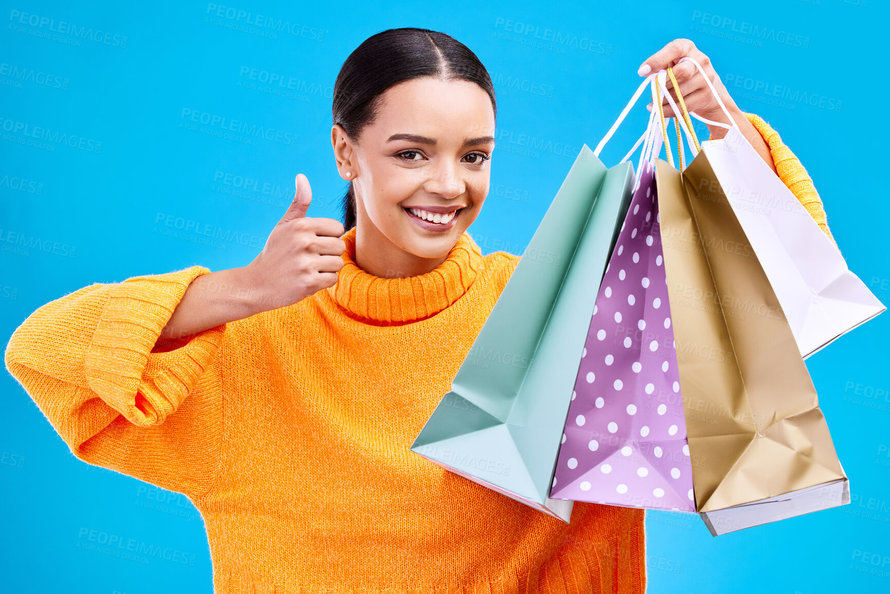 Buy stock photo Happy woman, shopping bags and thumbs up for purchase, sale or discount against a blue studio background. Portrait of female shopper holding gift bag showing thumb emoji, yes sign or like for items