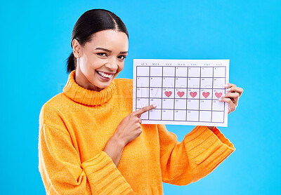 Buy stock photo Health, portrait and female with a calendar in a studio to track her menstrual or ovulation cycle. Happy, smile and face of a woman model pointing to a paper period chart isolated by blue background.