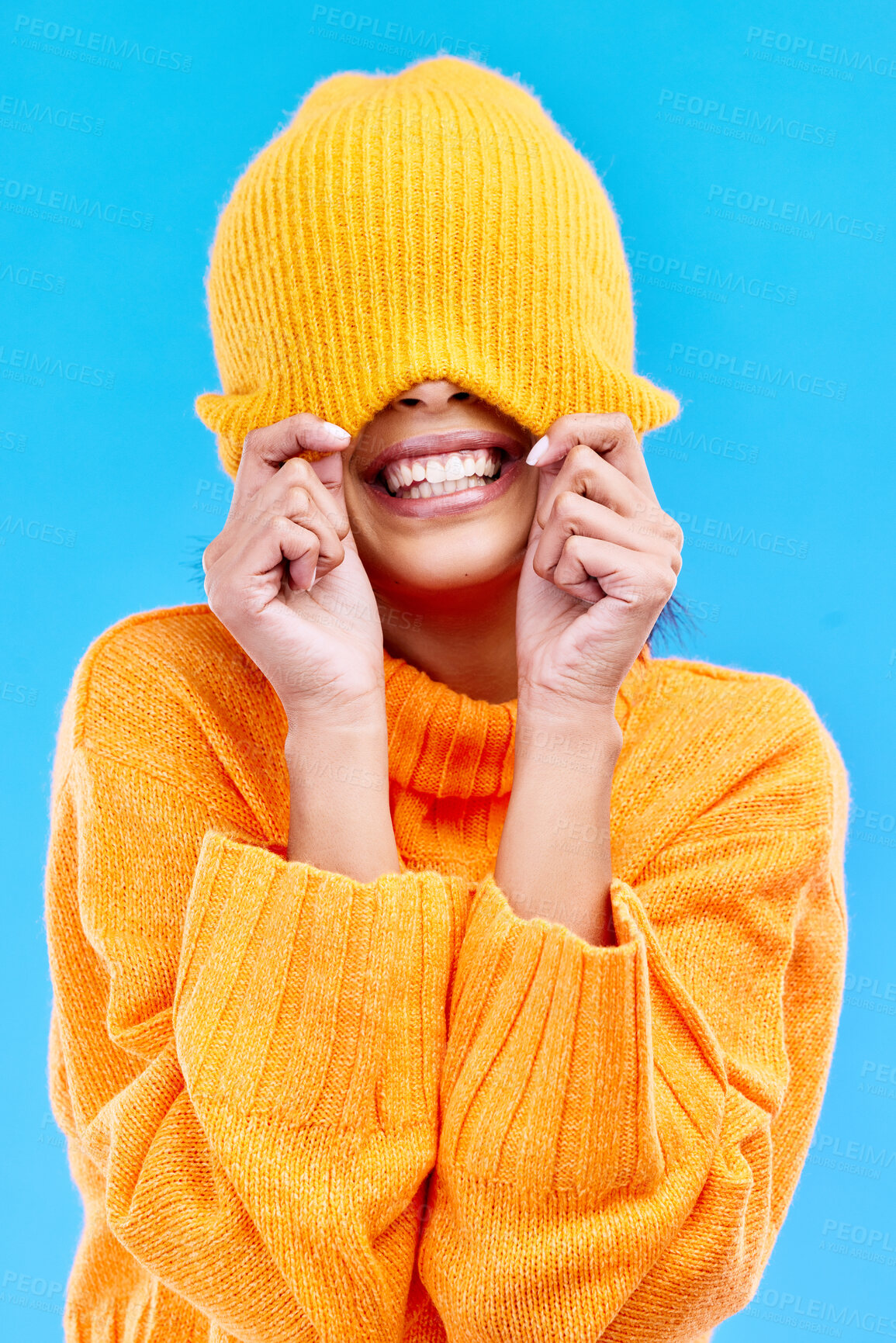 Buy stock photo Fashion, crazy and cover with woman and beanie in studio for hiding, winter and goofy. Playful, happiness and smile with female and knitted hat isolated on blue background for funny, silly and cool