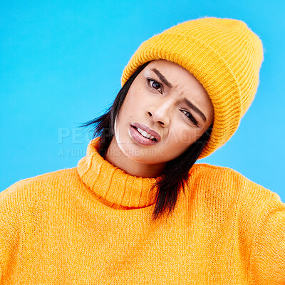 Buy stock photo Portrait of woman in winter fashion with confusion, beanie and doubt isolated on blue background. Style, funny expression on face and gen z girl on studio backdrop with warm clothing for cold weather