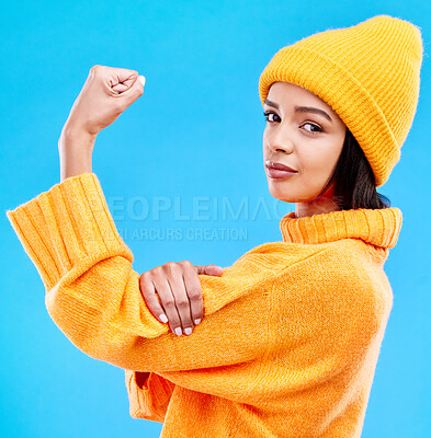 Buy stock photo Portrait of woman in winter fashion with power, beanie and glasses isolated on blue background. Style, arm flex and gen z girl in studio backdrop with strong face and warm clothing for cold weather.