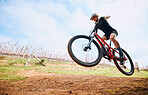 Bicycle jump, countryside and woman on a bike with speed for sports race on a gravel road. Fitness, exercise and fast athlete doing sport training in nature on a park trail for cardio and workout