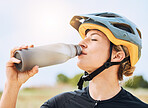 Woman drinking water, bottle and cycling with exercise outdoor, helmet for safety and health with hydration. Athlete, biking and female with healthy and active lifestyle, fitness and sports training