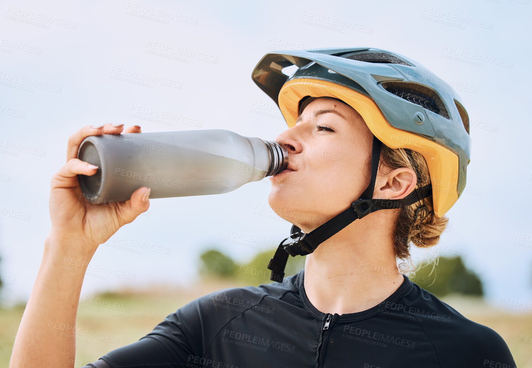 Buy stock photo Woman drinking water, bottle and cycling outdoor with fitness, helmet for safety and health with hydration. Athlete, biking and female with healthy and active lifestyle, drink liquid and training