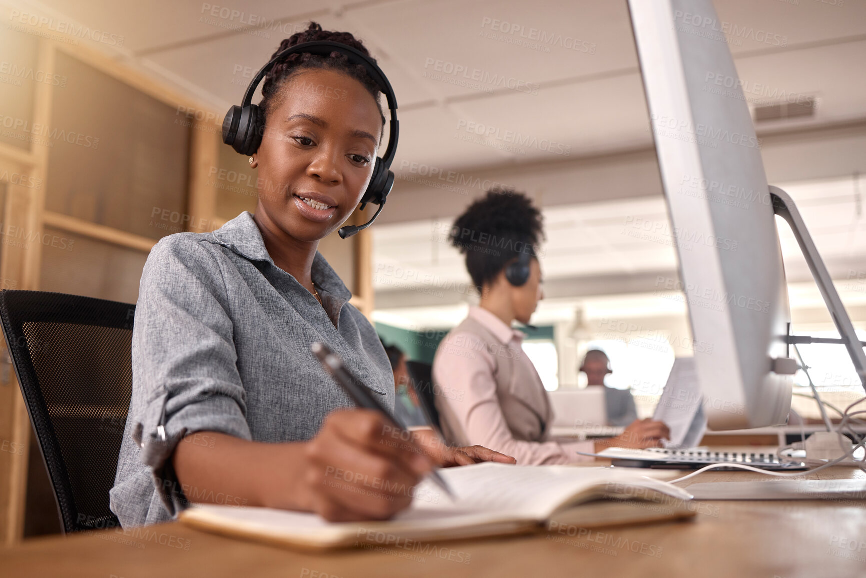 Buy stock photo Call center, woman and writing at computer on desk in office for sales and customer service notes and information, African female agent or consultant in telemarketing, support and crm with notebook