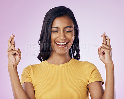 Buy stock photo Fingers crossed, wish and woman in a studio with hope, prayer or faith for success or achievement. Happy, smile and Indian female model with a luck hand gesture or sign isolated by purple background.