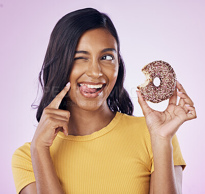 Buy stock photo Donut, dessert and wink with woman in studio for diet, snack and happiness. Sugar, food and smile with female eating chocolate treat isolated on pink background for nutrition, playful and craving