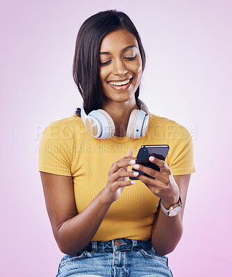 Buy stock photo Music, phone and Indian woman typing on pink background for social media, website and chatting. Relax, happy and isolated girl streaming audio, radio and track on smartphone for message on mobile app
