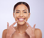 Portrait or happy woman pointing to teeth, lipstick or dental hygiene with a smile on white background. Face, teeth whitening results or girl beauty model smiling after dentist mouth cleaning checkup