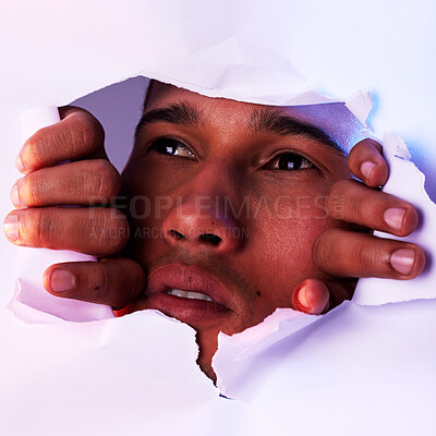 Buy stock photo Face, wall and a man looking through a hole to discover, explore or search while on an adventure. Head, eyes and thinking with a handsome young male closeup in studio to look out from a tear or gap