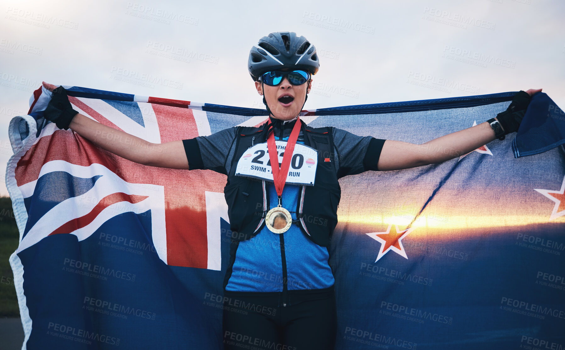 Buy stock photo Winner sports, happy woman and flag with gold medal for winning outdoor cycling race or New Zealand triathlon. Happiness, win and success cyclist in wow, fitness and world record with national pride.