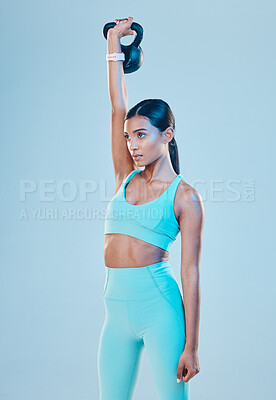 Buy stock photo Kettlebell, exercise and woman training, fitness and focus for wellness, healthy lifestyle and cardio against a blue studio background. Female athlete, model and person with gym equipment and strong
