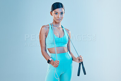 Buy stock photo Fitness, skipping rope and mockup with a sports woman in studio on a blue background for health or wellness. Exercise, mindset and space with a young female athlete training for cardio or endurance