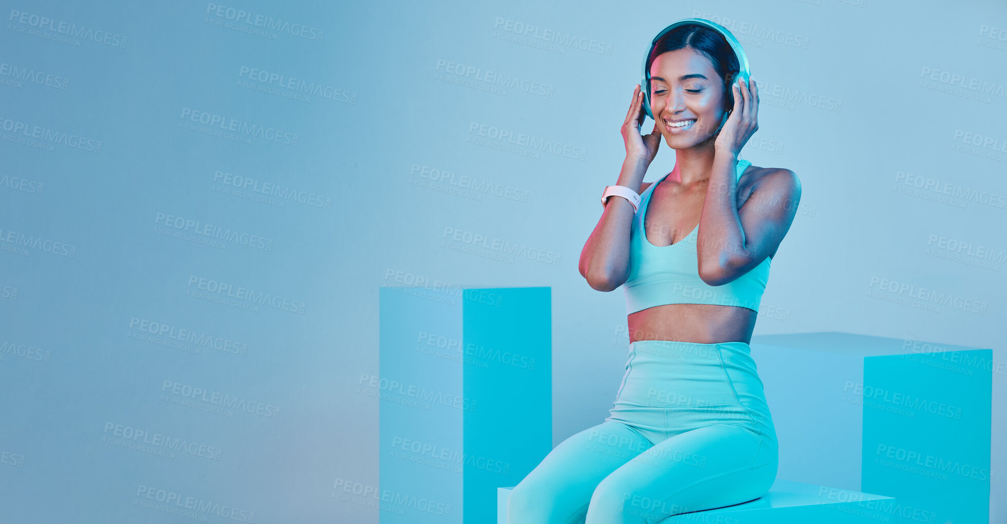 Buy stock photo Mockup, fitness and woman with headphones, smile and exercise against a blue studio background. Female model, joy and person with headset, workout and streaming music with happiness, sports and radio