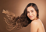 Hair, beauty and portrait of woman in studio for wellness, hairstyle treatment and health on brown background. Salon aesthetic, smile and face of happy girl with cosmetics, keratin and natural style