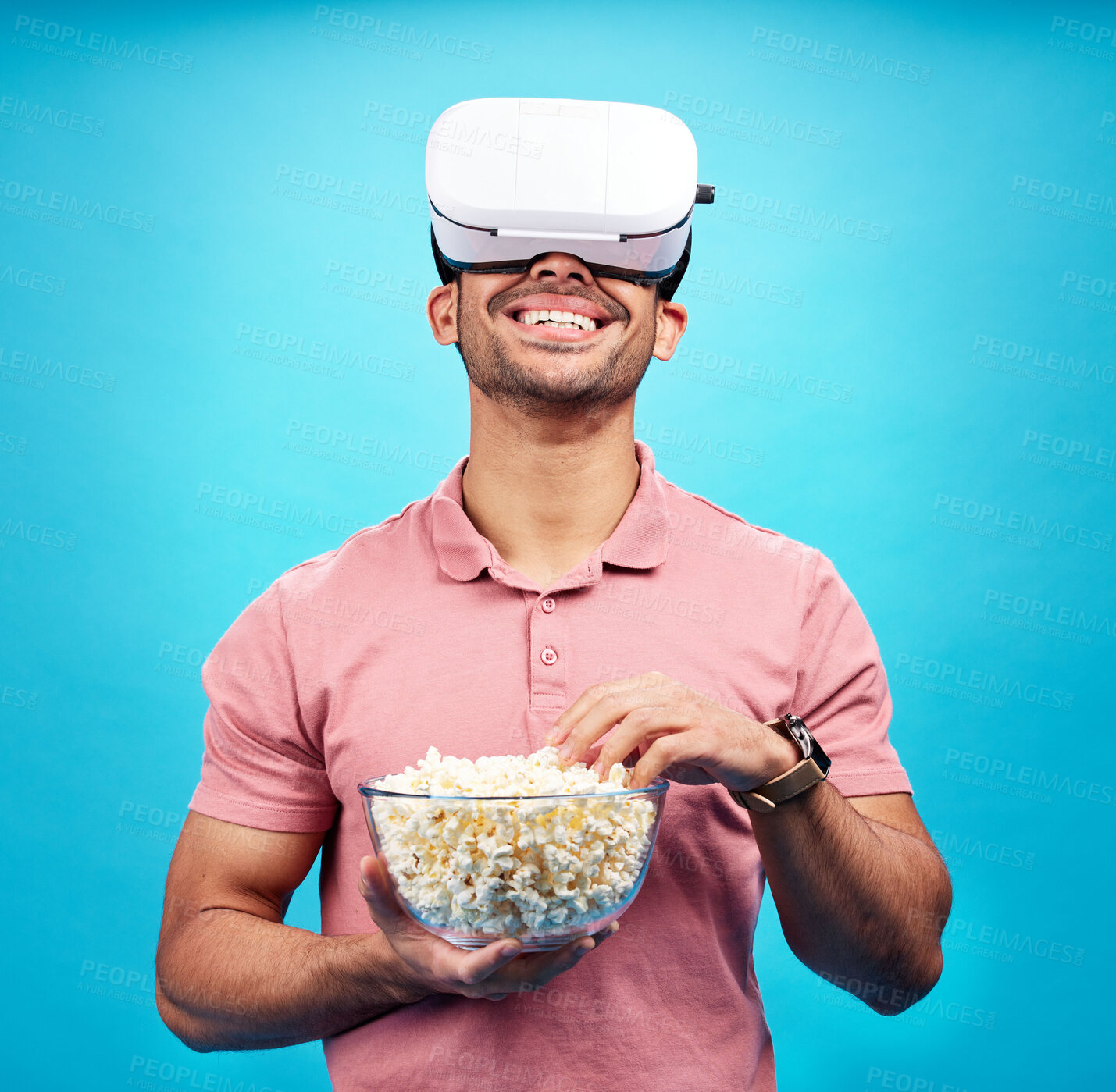Buy stock photo Vr, popcorn and movie with man in studio for streaming, met verse and cinema. Happy, technology and digital with male watching tv on blue background for virtual reality, television and future theater