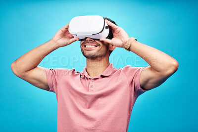 Buy stock photo Man with smile, virtual reality and metaverse with futuristic tech, UX and simulation isolated on blue background. Future technology, digital world and gaming male in VR goggles streaming in studio