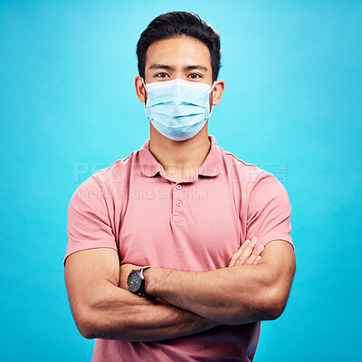 Buy stock photo Man in face mask, arms crossed in portrait and covid, safety from virus, bacteria and germs isolated on blue background. Disease, corona and male person, health compliance with protection in studio