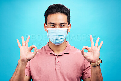 Buy stock photo Man in face mask, portrait and corona with okay hand sign, safety from virus and bacteria isolated on blue background. Disease, covid and male person with emoji and health compliance in studio