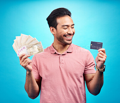 Buy stock photo Smile, money and credit card by happy man in studio with savings, finance or investment growth on blue background. Cash, joy and asian guy excited for banking, success or financial freedom isolated