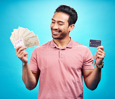 Buy stock photo Credit card, smile and money by happy man in studio with savings, finance or investment growth on blue background. Cash, profit and asian guy excited for banking, loan or financial freedom isolated