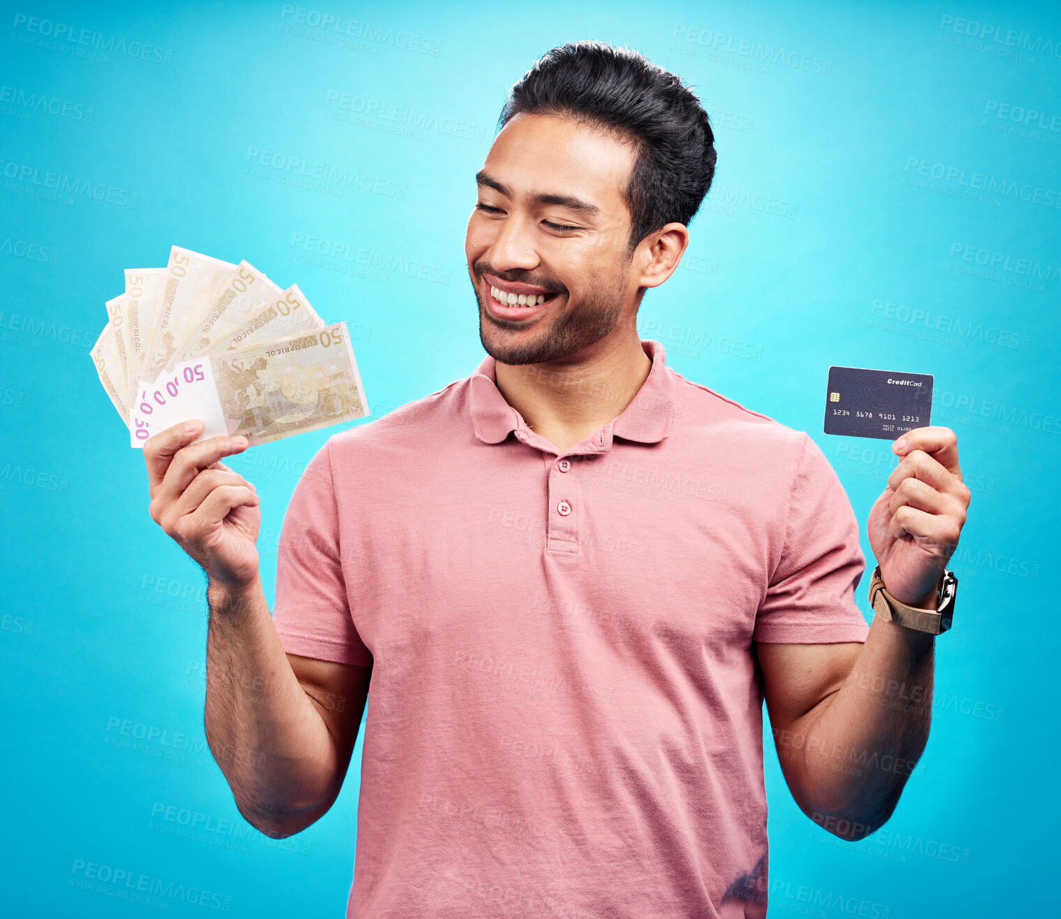 Buy stock photo Credit card, smile and money by happy man in studio with savings, finance or investment growth on blue background. Cash, profit and asian guy excited for banking, loan or financial freedom isolated