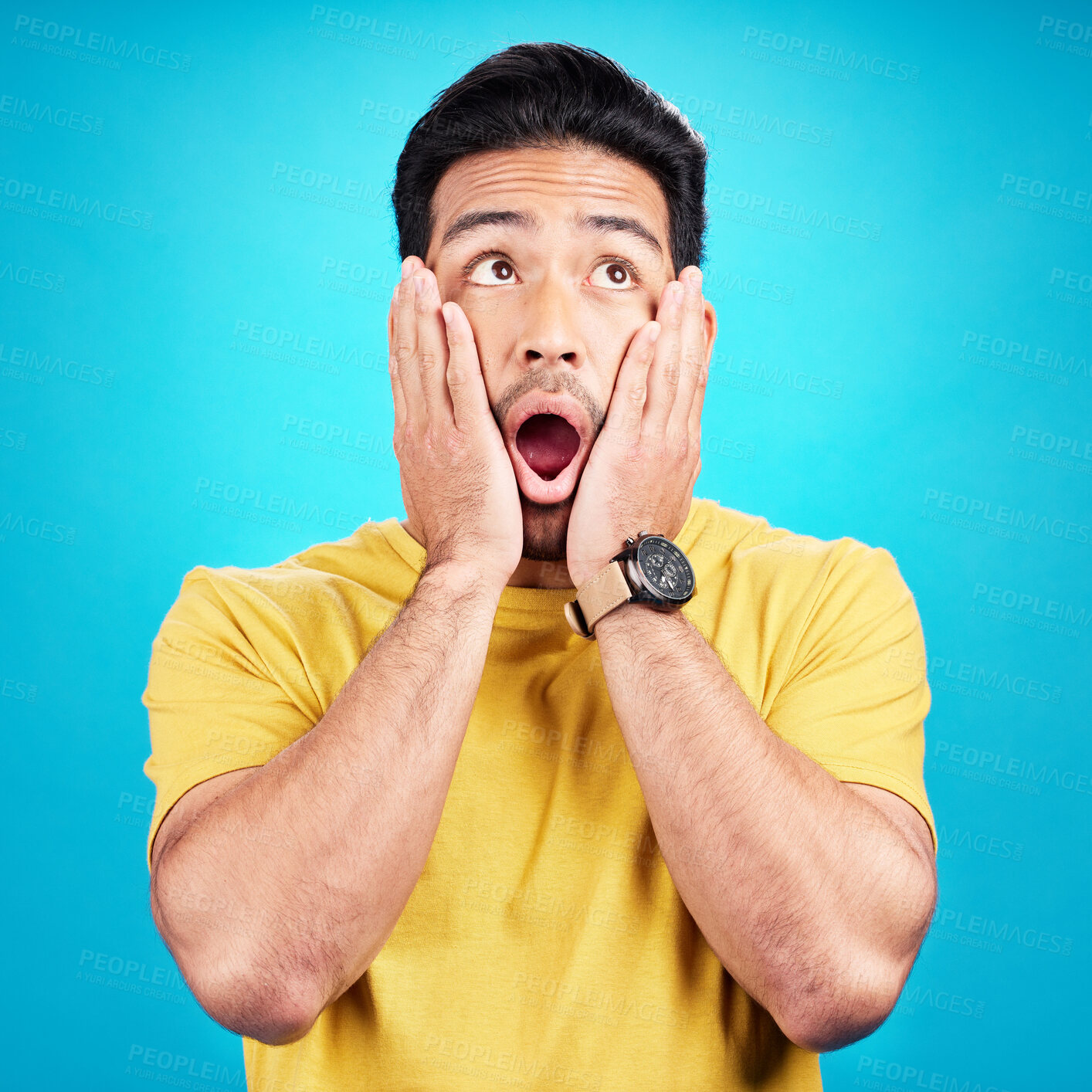Buy stock photo Wow, shocked and man with hands on face and mouth open for surprise or announcement in studio. Male model person on a blue background while thinking of gossip, sale or promotion with comic emoji