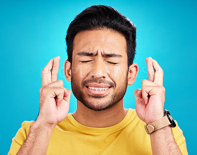 Buy stock photo Luck, man and fingers crossed for hope in studio isolated on a blue background. Wish, hand gesture and male person with aspiration, hopeful emoji or wait for good fortune, results or optimistic faith