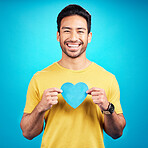 Portrait, cutout heart and Asian man with happiness, loving and emoji with guy against a blue studio background. Face, male person and model with symbol for love, smile and carefree with support