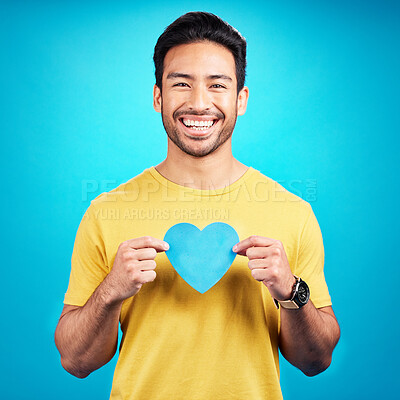 Buy stock photo Portrait, cutout heart and Asian man with happiness, loving and emoji with guy against a blue studio background. Face, male person and model with symbol for love, smile and carefree with support