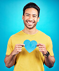 Portrait, cutout heart and Asian man with support, wellness and confident person against blue studio background. Face, male model or guy with symbol for love, cheerful and emoji with smile and loving