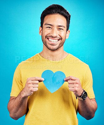 Buy stock photo Portrait, cutout heart and Asian man with support, wellness and confident person against blue studio background. Face, male model or guy with symbol for love, cheerful and emoji with smile and loving