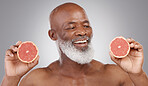 Senior black man, grapefruit and smile for skincare, natural nutrition or vitamin c against a gray studio background. Happy African American male holding fruit for healthy skin, diet or wellness