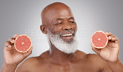 Buy stock photo Senior black man, grapefruit and smile for skincare, natural nutrition or vitamin c against a gray studio background. Happy African American male holding fruit for healthy skin, diet or wellness