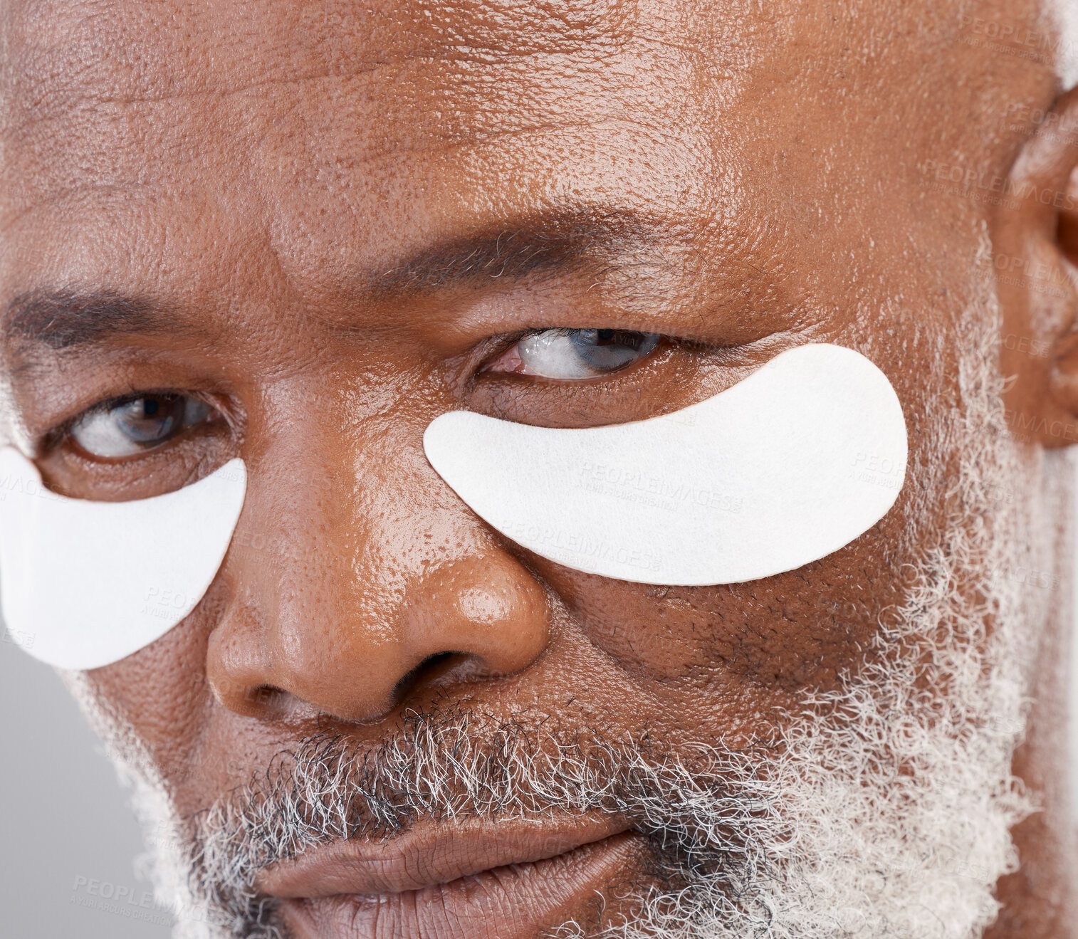 Buy stock photo Skincare, eye mask and zoom on portrait of man with serious face and professional anti ageing spa treatment.  Dermatology, cosmetic collagen routine and mature African model with skin care on eyes.