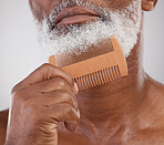 Man, hands and comb on beard for grooming, beauty or skincare hygiene against a studio background. Closeup of senior male neck and chin combing or brushing facial hair for clean wellness or haircare