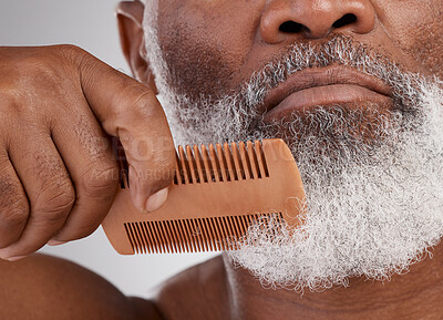 Buy stock photo Senior black man, hands and beard with comb in grooming, beauty or skincare hygiene against a studio background. Closeup of African elderly male face combing or brushing facial hair in clean wellness