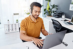 Laptop, headphones and business man listening to music, audio and working. Asian male entrepreneur at desk with a smile while typing for research, email or social media with internet connection