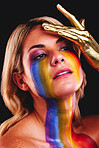 Woman, beauty face and gold color paint and cosmetics on skin in studio. Female model person on a black background for art deco, fantasy and creative rainbow makeup with metallic hand on head