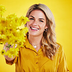 Portrait, smile and woman showing flowers in studio isolated on a yellow background. Floral, bouquet present and happiness of person or female model sharing natural plants and fresh flower for spring