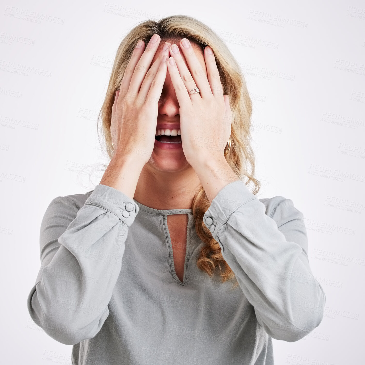 Buy stock photo Comic, funny and embarrassed with a woman on a gray background in studio laughing at a joke. Smile, comedy and humor with a person enjoying a laugh or fun while covering her face in expression