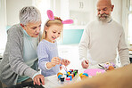 Easter, art and a girl painting with her grandparents in their home for love, bonding or celebration together. Family, kitchen or egg with a senior couple and their grandchild in a house to paint