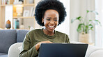 Female enjoying a comedy movie on her laptop while eating a big bowl of popcorn at home. African woman laughing while watching funny movies on her couch. Young lady streaming online