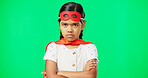 Angry, crossed arms and face of child on green screen with upset, disappointed and anger expression. Portrait, mockup studio and young girl in superhero costumer with mad, unhappy and shake head